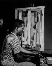 一个男人站在一幅画前的黑白照片