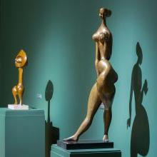 约翰·罗登在基座上的两件青铜作品的装置照片. 画廊和基座被漆成绿色. 前景中的作品, “夜”, 一个裸体的女性形象在跳舞的姿势，右手拿着球吗. 背景中的作品是一个抽象的人物——克松. . 