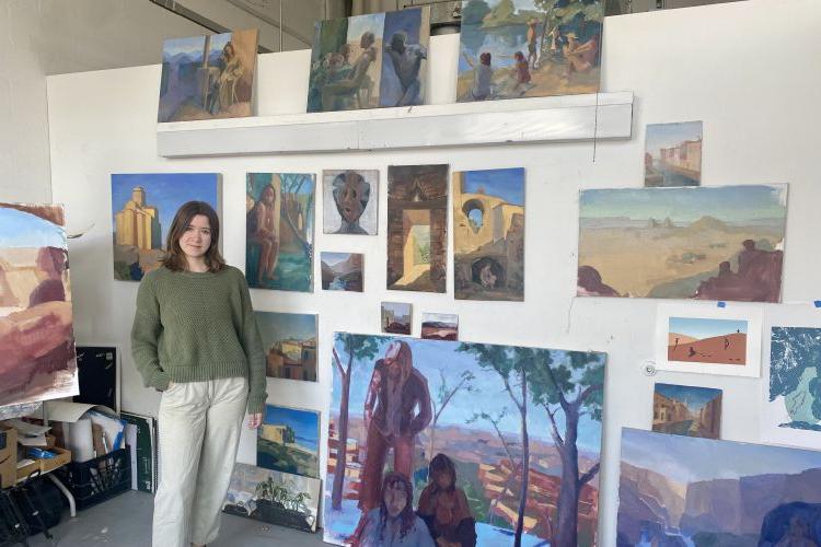 Anna Hoppel in her studio posing with her paintings.